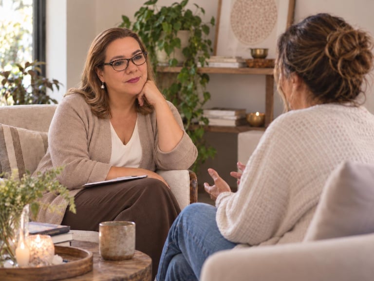 Two women having a conversation in a cozy living room with plants and warm lighting
